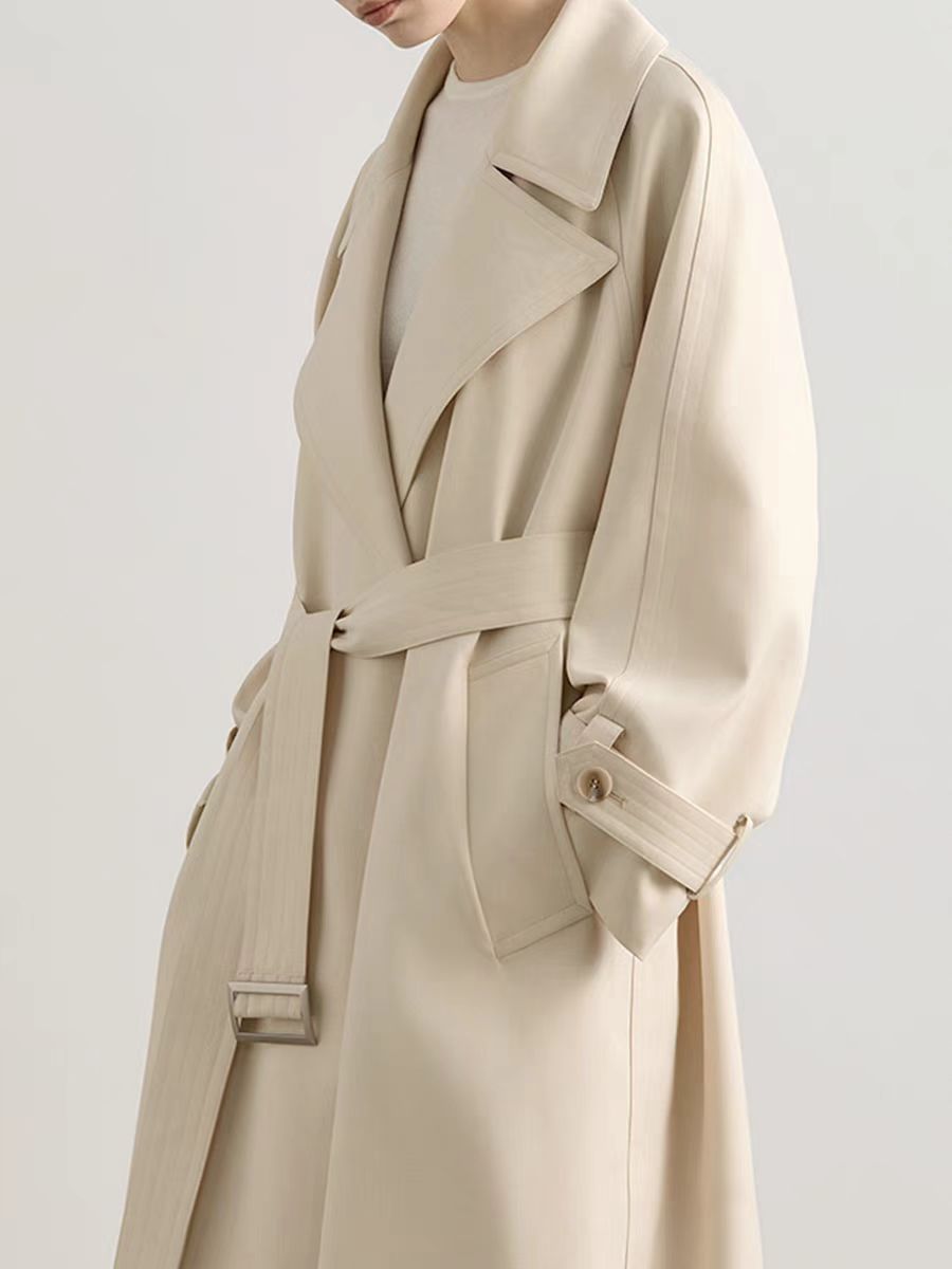 Long beige trench coat with classic belted design and tailored fit, displayed on a mannequin.